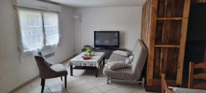 a living room with a table and chairs and a television at Appartement charmant près du lac à Saint-Point-Lac in Saint-Point-Lac
