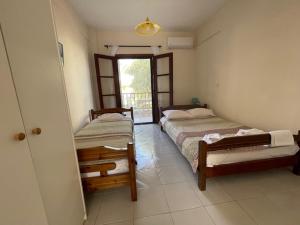 een slaapkamer met 2 bedden en een deur naar een balkon bij House Nativa in Mola Kalyva