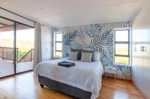 a bedroom with a large bed and a balcony at The Whalehouse in Wilderness