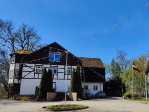 a large black and white building with a flag on it at Baltakmeņu muiža in Mujani +12 photos