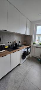 a kitchen with a washing machine and a sink at Przytulny domek in Mielno