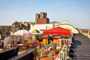 balkon ze stołami, krzesłami i parasolami w obiekcie Mama Shelter Rennes w mieście Rennes