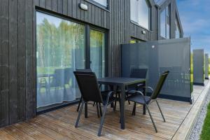 a black table and chairs on a wooden deck at KUTI apartamentai in Palanga