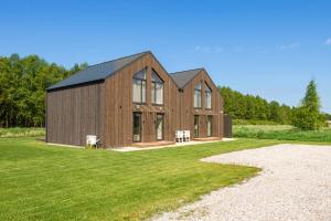 a large wooden house on a grass field at KUTI apartamentai in Palanga