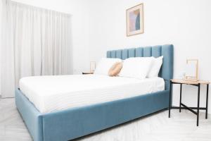 ein blaues Bett in einem weißen Zimmer mit einem Beistelltisch in der Unterkunft ChrisAri House in Zipárion