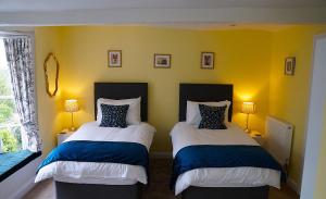 two beds in a room with yellow walls at Radcliffe Guest House in Ross on Wye