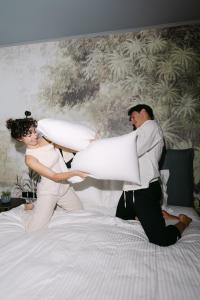 a man and woman jumping on a bed with pillows at AIRIO Athens Luxury Suites in Athens