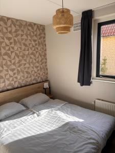 a bedroom with a bed and a window at Zeer comfortabel vakantiehuis op kleinschalig park 6 personen in Ewijk