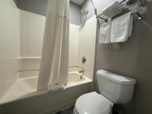 a white bathroom with a toilet and a tub and a sink at Studio 6 Tacoma, WA - South in Tacoma