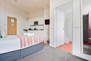 a bedroom with a large bed and a kitchen at Cosy Studio Flat Near Town Centre & Parking in Dudley