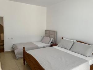 two beds in a room with white walls at Qirjako's Rooms in Himare