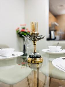 a glass table with white plates and a vase on it at Vista Luxury Home With Parking in Ajman 