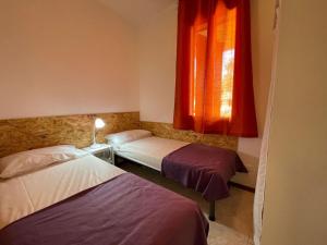 una camera con due letti e una finestra con tende rosse di Villa with private garden and barbecue a Porto Santa Margherita di Caorle Altre 14 foto