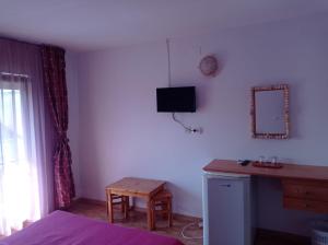 a bedroom with a desk and a tv on the wall at Pensiunea Orion in Costinesti
