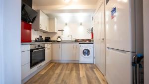 a kitchen with white cabinets and a washer and dryer at The Bard Apartment - Stratford upon Avon in Stratford-upon-Avon