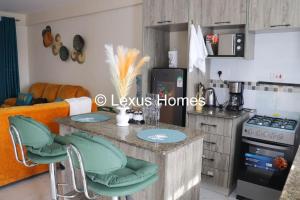 Una cocina con un mostrador con sillas verdes. en Lexus Homes, en Nakuru