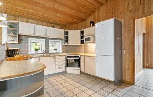 a kitchen with white appliances and wooden walls at Amazing Home In Blåvand With Sauna in Blåvand