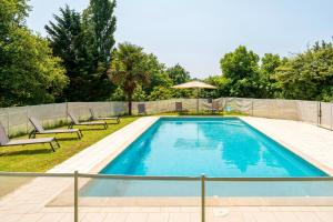 a swimming pool with two chairs and an umbrella at La Caseta in Estang