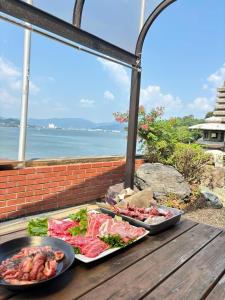 two trays of food on a wooden table with the ocean at MiLiS 自分を取り戻す湖畔の時間 in Ōsaki +17 photos