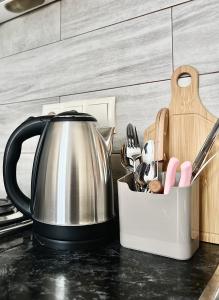 a tea kettle on a counter with a container of utensils at Cozy studio with a balcony and sea view in Batumi