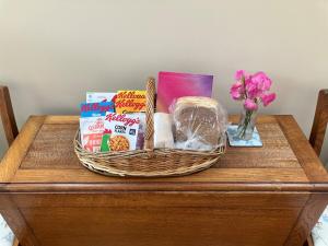 a basket on a table with snacks and a vase of flowers at Holly cottage in Stoke Rivers