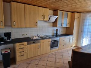 a kitchen with wooden cabinets and a sink at Ferienwohnungen März in Söchtenau