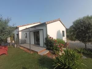 a small white house with a porch in a yard at Le Logis de la Voie Verte in Saint-Amadou
