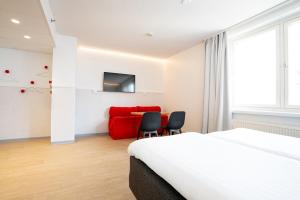 a hotel room with a bed and a red couch at Omena Hotel Jyväskylä in Jyväskylä