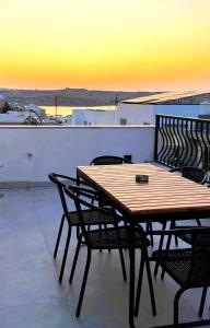 a wooden table and chairs on a balcony with a sunset at Stylish Side Seaview Penthouse By Quicktrips in St. Paul's Bay