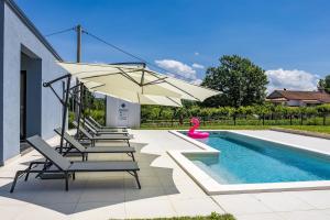 a pool with chairs and an umbrella next to a swimming pool at Villa Hera with Private Pool in Istria Quiet Location and Modern Design in Orbanići