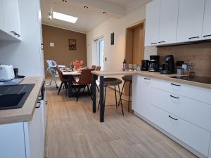 a kitchen with white cabinets and a table with chairs at Chez Camil in La-Roche-en-Ardenne