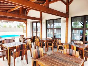 a restaurant with wooden tables and chairs and a pool at Lotusul Deltei in Murighiol +34 photos