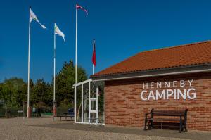 a bench in front of a building with flags at Henneby Camping - hytter in Henne Strand +4 photos