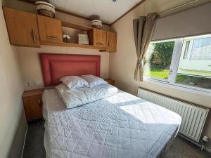 a bedroom with a bed with a red headboard and a window at Lovely 6 Berth Caravan For Hire At Manor Park In Hunstanton Norfolk Ref 23044S in Hunstanton +17 photos