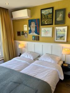 two beds in a bedroom with pictures on the wall at Boutiquehotel B&B the SJinn in Schin op Geul