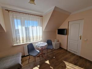 a living room with a table and chairs and a window at Pensjonat Elżbieta in Łeba