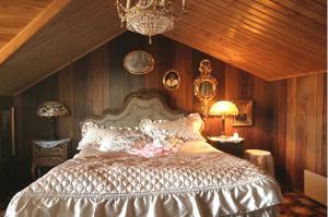 a bedroom with a bed with wooden walls and a chandelier at Hotel Villa Antonius in Naantali