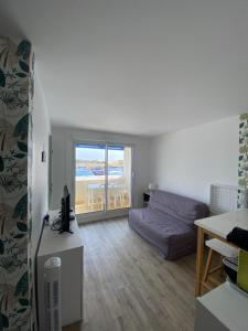 a living room with a bed and a desk with a computer at Cosy T2 RDC Résidence Bleu Marine in Lacanau-Océan