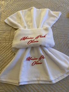 a white towel with red writing on it on a bed at Marina Park OLIWIA in Sveti Vlas