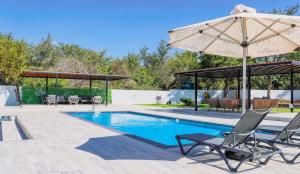 a swimming pool with two chairs and an umbrella at Kingdoms Lodge in Groblersdal