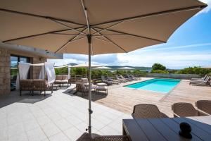 un patio con ombrellone e sedie e una piscina di La Villa Ghijuvani - Piscine Privée avec Vue Mer a Pianottoli-Caldarello Altre 17 foto
