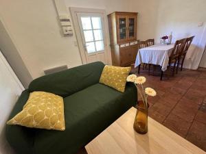 a living room with a green couch and a vase with flowers at Le gîte de mia in Luxey