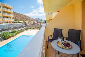 a balcony with a table with wine glasses and a pool at Apartman Mar Primavera in Arona