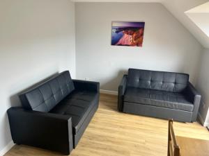 a living room with two black couches in a room at Causeway Coast Apartment in Ballycastle