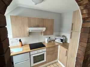 a kitchen with wooden cabinets and a stove top oven at Causeway Coast Apartment in Ballycastle