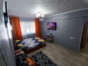 a bedroom with a bed and a tv on a wall at Квартира комфорт, район ЖД вокзал in Balqash