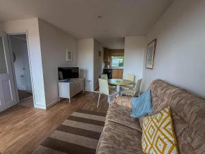a living room with a couch and a table at Chalet With Free Wifi At Rainbows End Near A Lovely Norfolk Beach Ref 31002R in Bacton