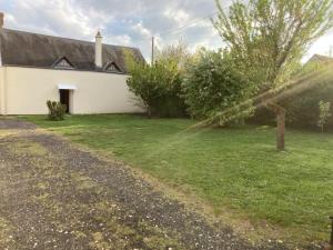 a house with a grassy yard next to a building at Charming quiet house in La Vernelle