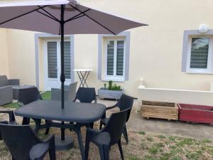 a patio with a table and chairs and an umbrella at Charming quiet house in La Vernelle