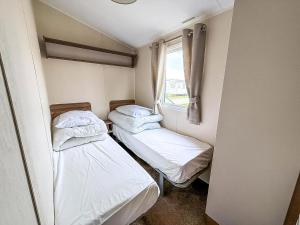 twee bedden in een kleine kamer met een raam bij Caravan In Scratby, Norfolk Ref 50071D in Great Yarmouth